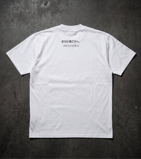 White t-shirt laid flat displaying Japanese text and English phrase on the back against a concrete background