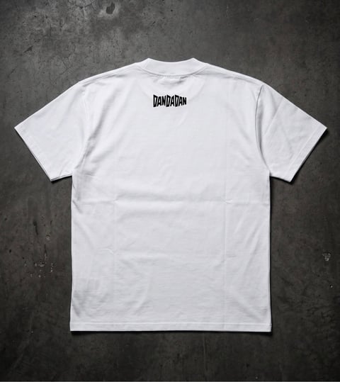 White t-shirt with DamDamn logo printed on back, displayed flat on gray concrete background