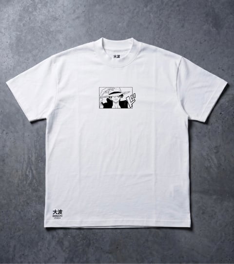 White t-shirt with black manga-style cartoon graphic on chest and Japanese text on sleeve, displayed flat on gray background